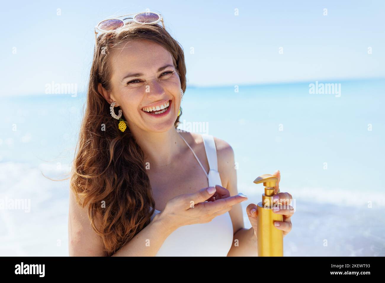 Ritratto di felice donna alla spiaggia in bianco beachwear utilizzando spf. Foto Stock