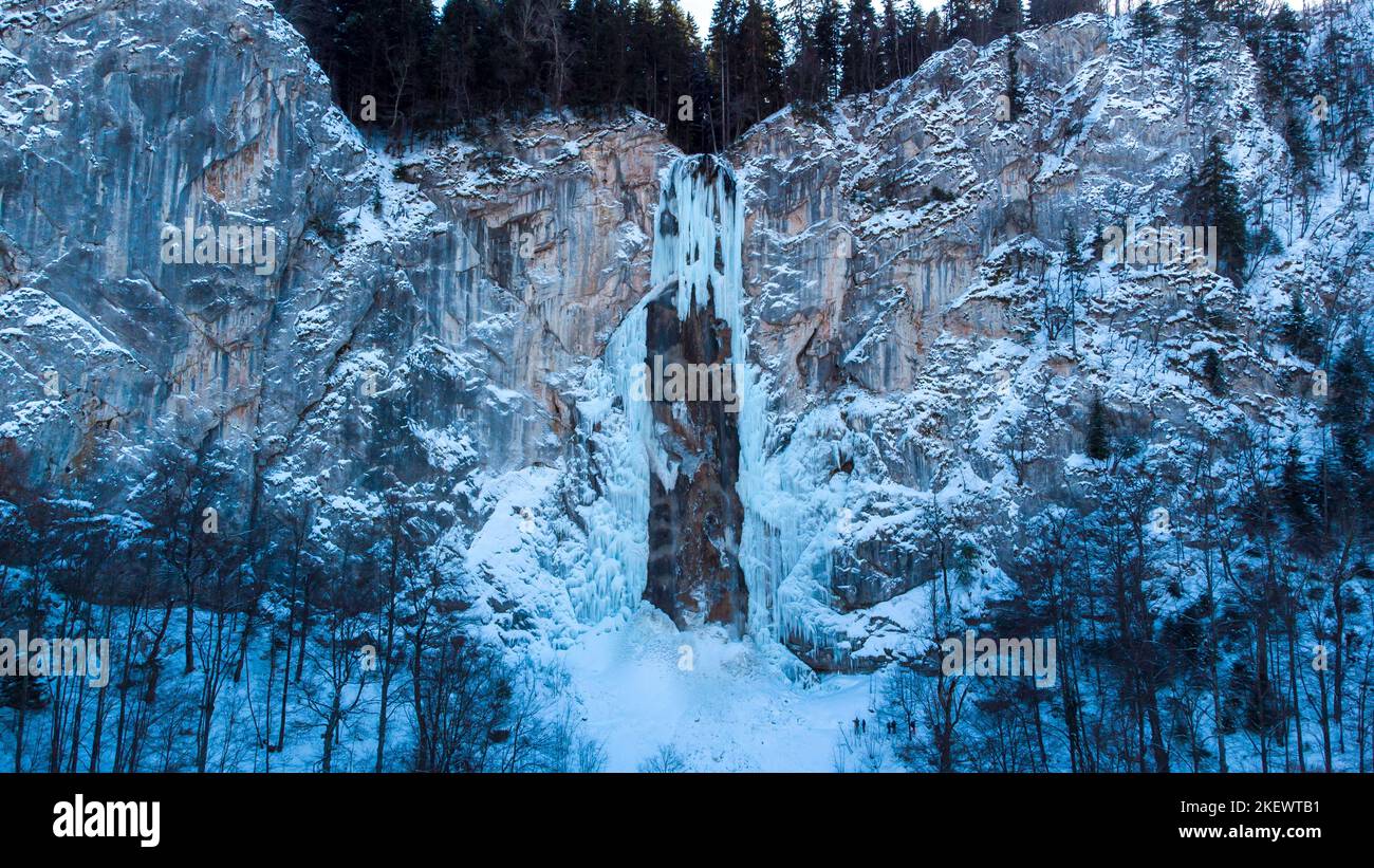 Vista aerea del drone della cascata ghiacciata con un po' d'acqua che scorre. Splendido e magico scenario delle vacanze invernali per gli amanti della natura. Foto Stock