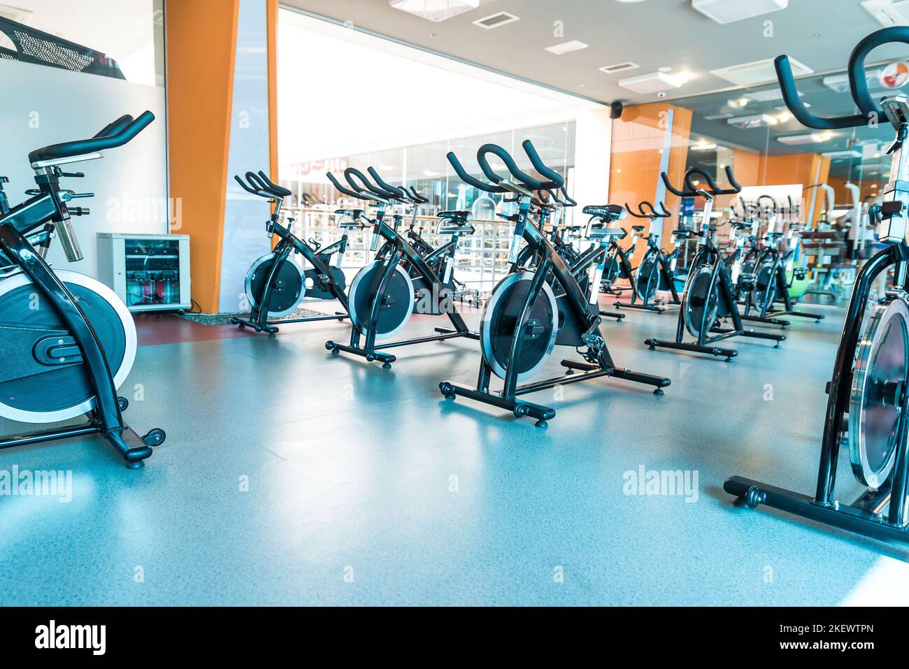 Moderno interno palestra con attrezzature. Fila di esercizi dettaglio bici, retroilluminazione. Concetto di stile di vita sano Foto Stock