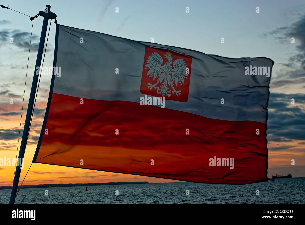 Bandiera polacca nel vento, bandiera marittima polacca, bandiera marittima della Polonia, sfondo cielo serale. Il flag attualmente valido nella navigazione civile. Foto Stock
