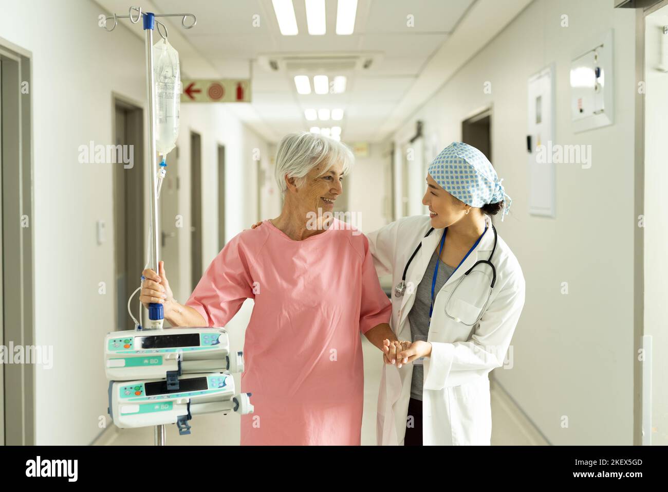 Medico femminile e paziente caucasico senior con asta iv parlare Foto Stock