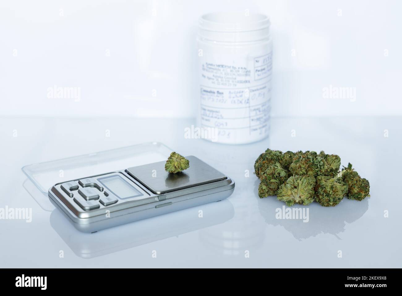 FLOS di cannabis, mucchio di marijuana medica accanto alla scala di precisione e contenitore bianco, modo sicuro per prendere la medicina Foto Stock