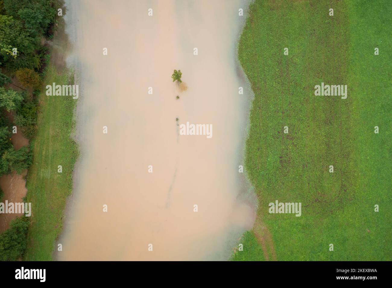 Fiume sulle rive che si immergono nei campi dopo la pioggia pesante, acqua che si avvicina alle case, tiro aereo dall'alto verso il basso. Foto Stock