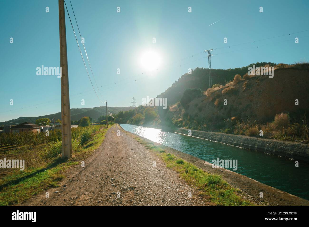 Strada sterrata vicino ad un canale d'acqua durante una giornata di sole Foto Stock