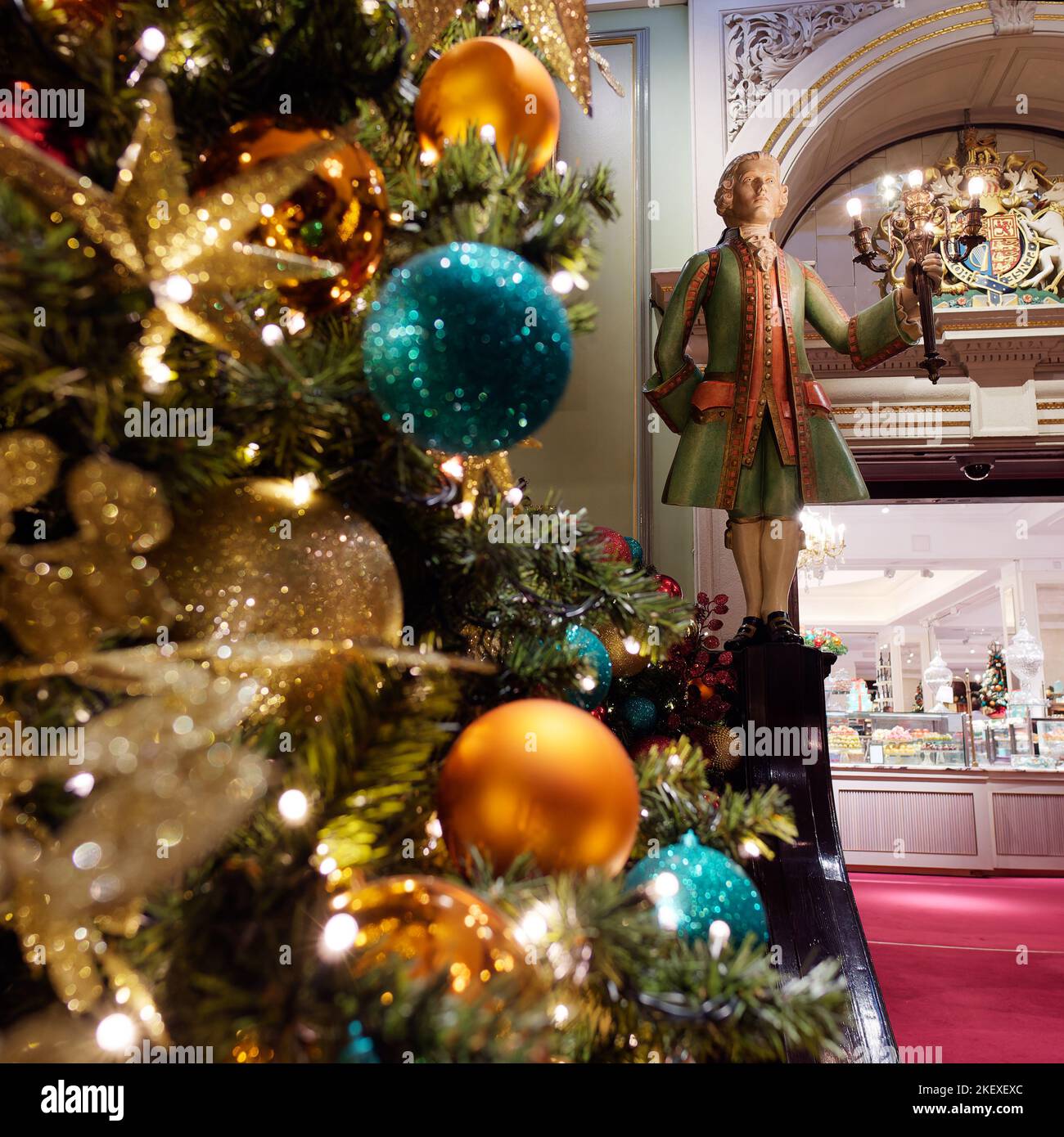 Albero di Natale decorato più una statua di un uomo che tiene una lampada all'ingresso del Fortnum e Mason Department Store a Piccadilly, Londra. Foto Stock