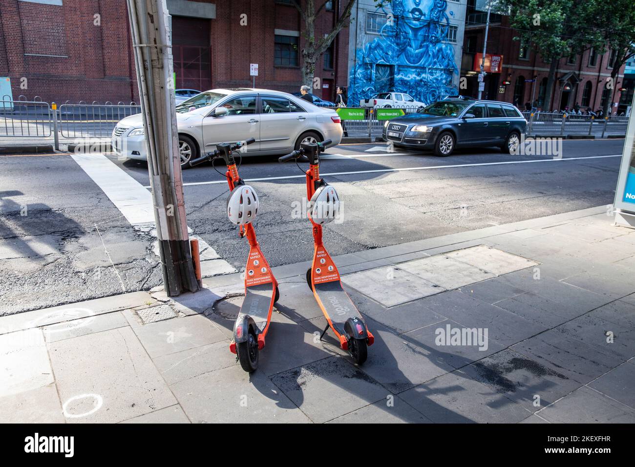 Scooter elettrici Neuron arancioni e con caschi a noleggio su un marciapiede nel centro di Melbourne, Victoria, Australia 2022 Foto Stock