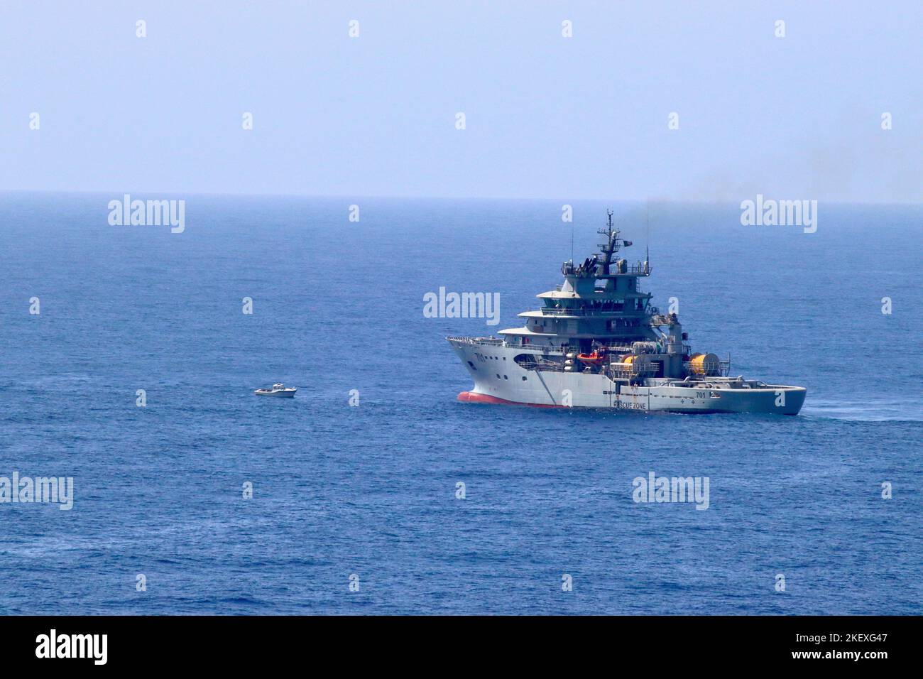 Algerian Naval Salvage Vessel 701 l'al-Munjid (El Mounjid) circola intorno ad una barca migrante abbandonata che si sbarca senza potere nel Mar Mediterraneo. Foto Stock