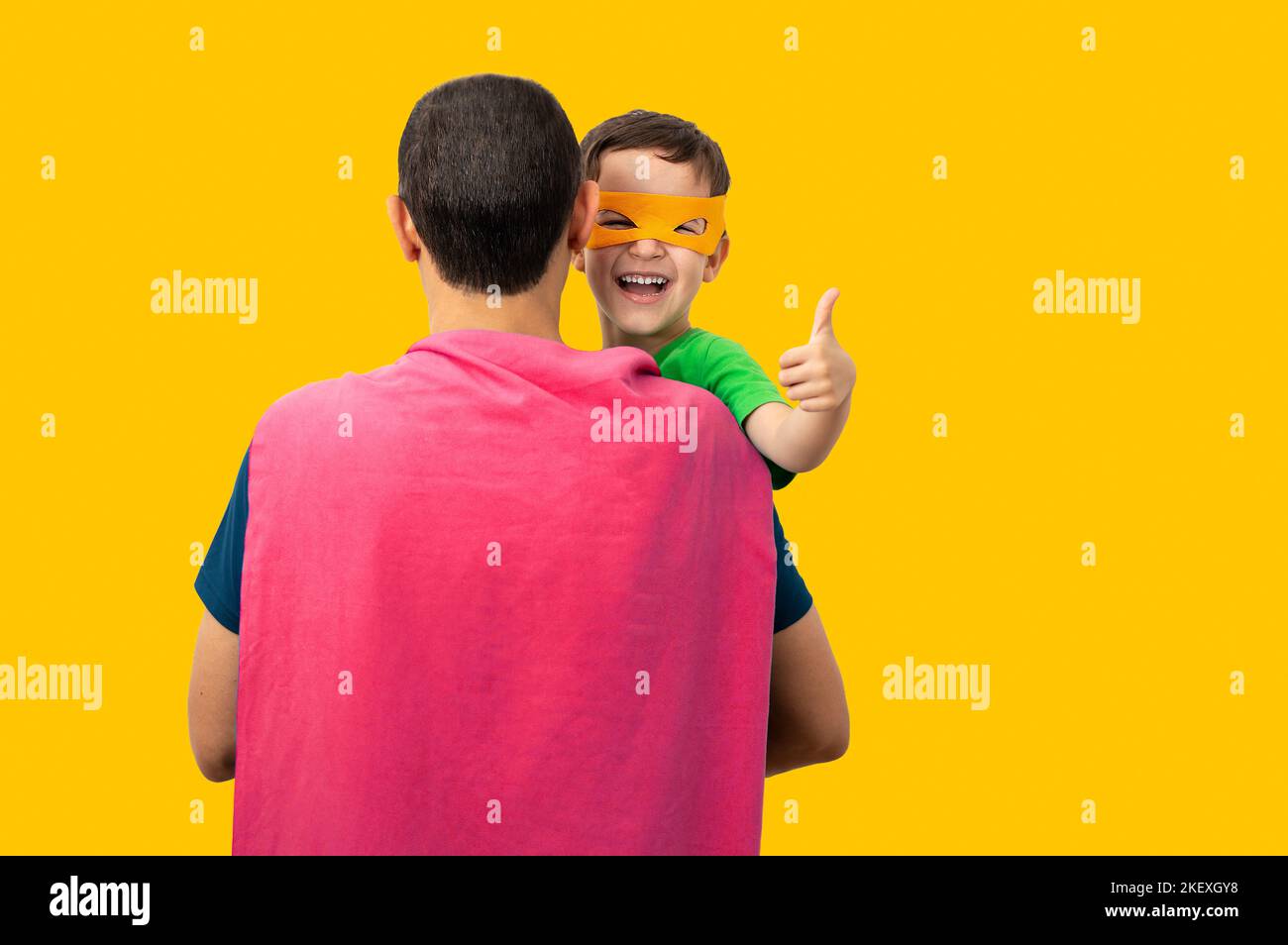 Il mio bel super dad.Kid fare pollici su segno con le mani ridendo felicemente con sfondo giallo. Foto Stock