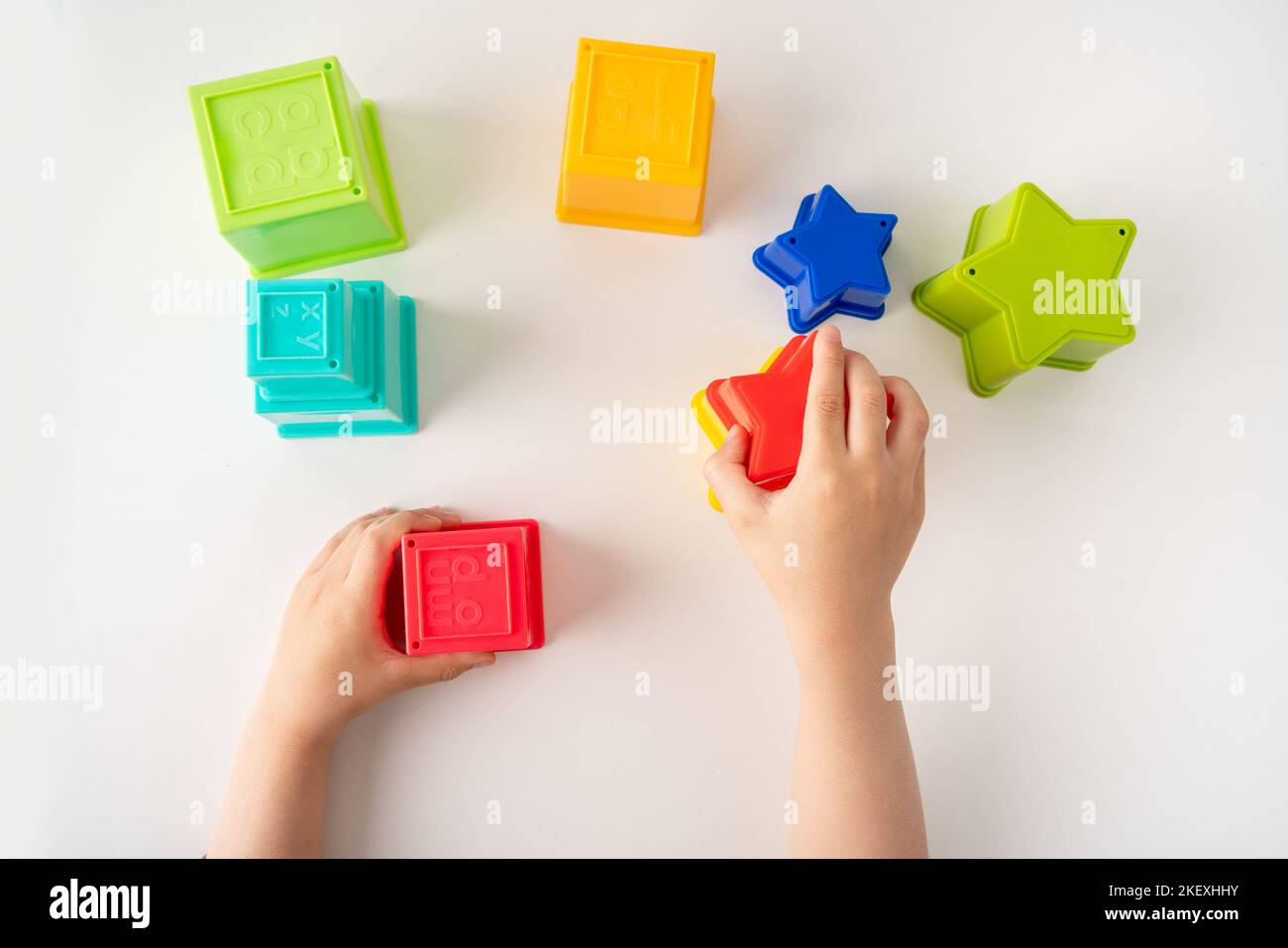 Colpo ad angolo alto di mani giocando con cubi giocattolo e stelle, giochi educativi Foto Stock