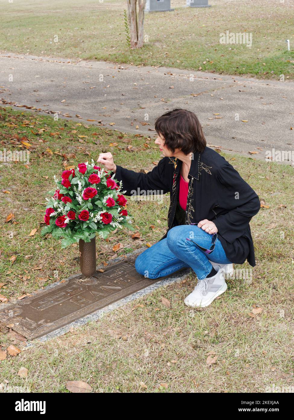 Donna matura che mette i fiori in un sito di tomba di famiglia, come un memoriale, in un cimitero a Montgomery Alabama, USA. Foto Stock