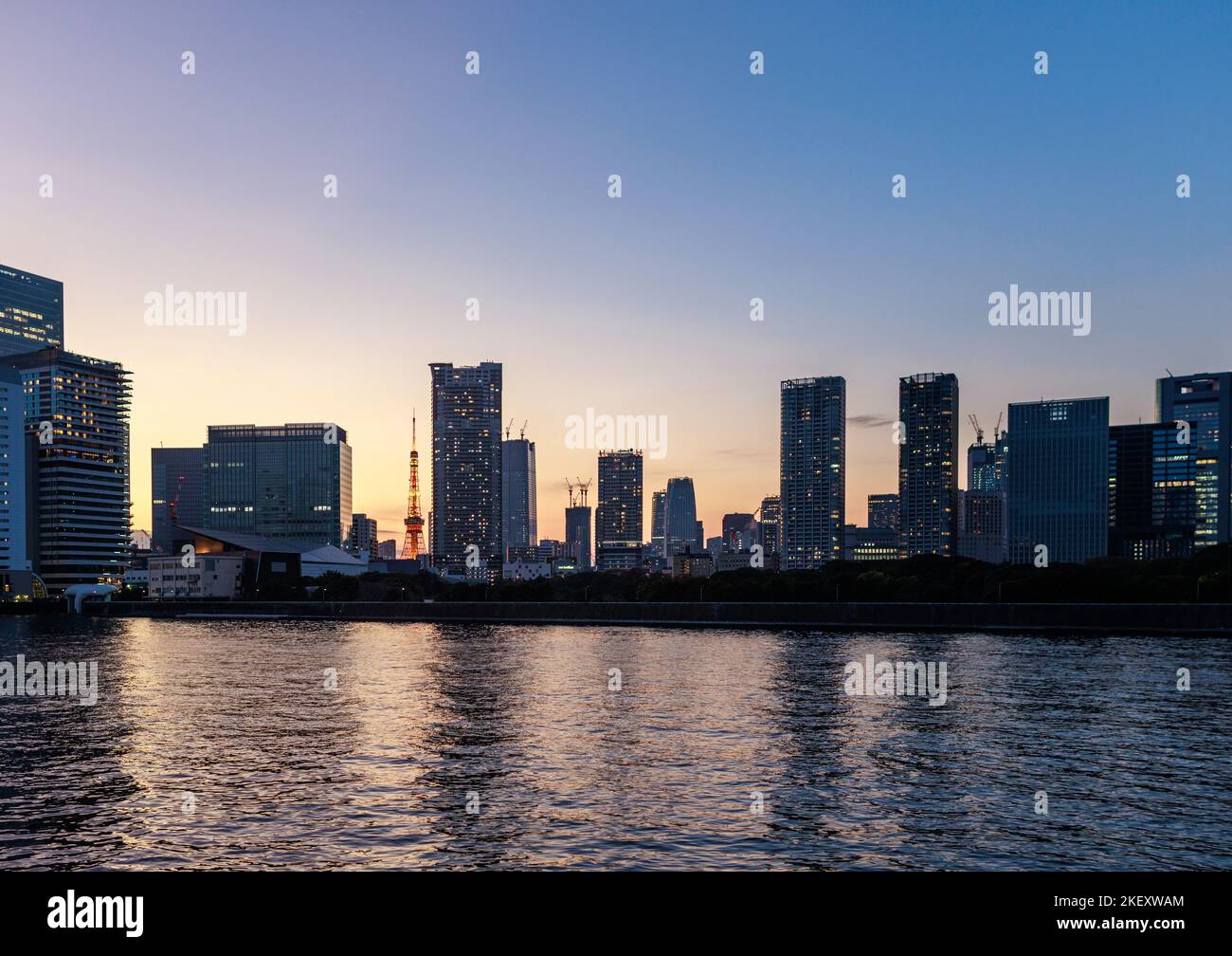 Tokyo torre attraverso alti edifici residenziali lungo il fiume al tramonto Foto Stock