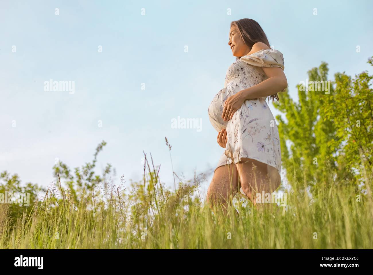 Donna incinta in 3rd trimestre respirando aria pulita durante la gravidanza in fresca primavera natura foresta. Ragazza asiatica che si aspetta pancia nella felicità Foto Stock