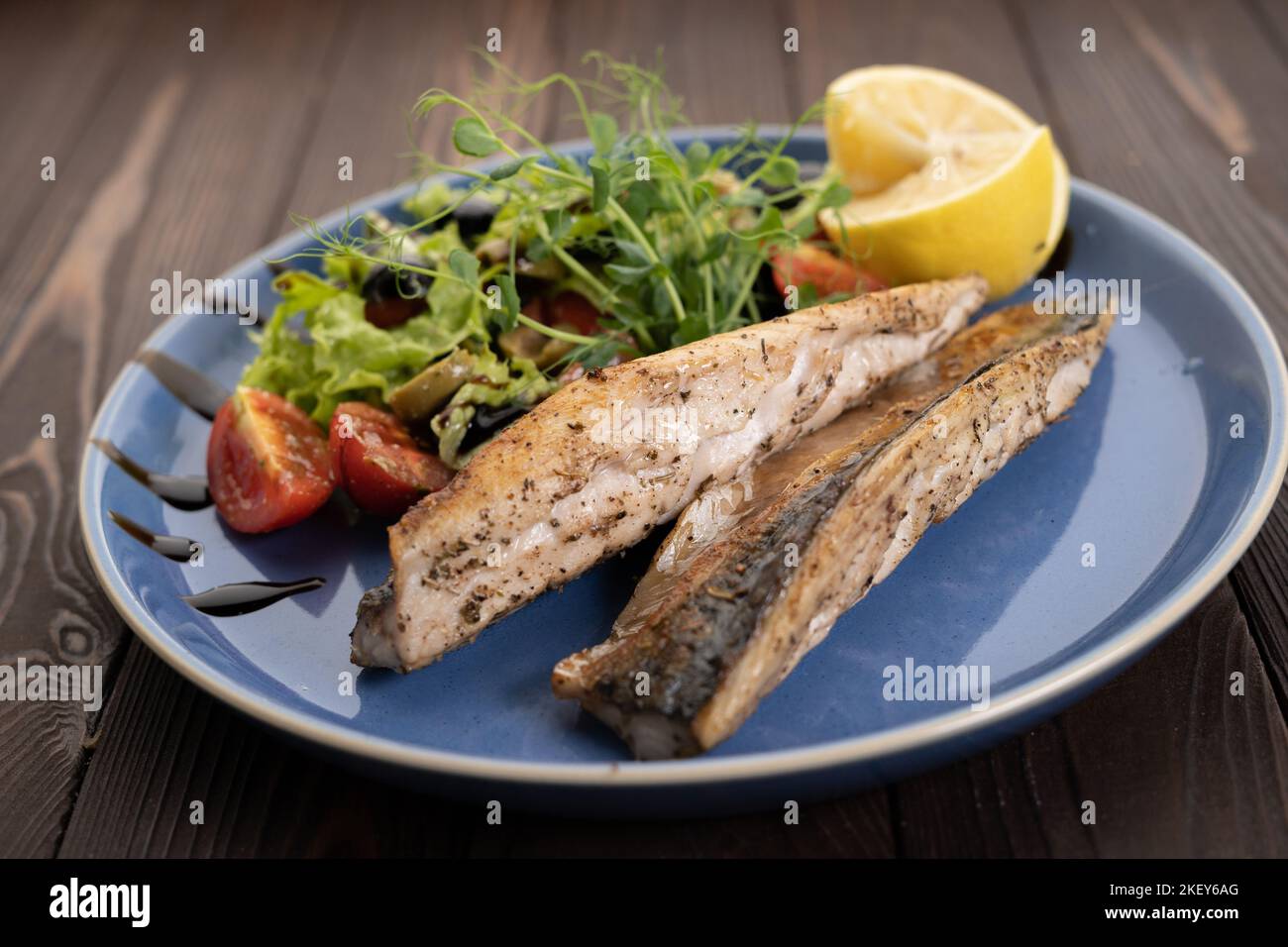 Barbecue sgombro grigliato di pesce con limone e pomodori sul piatto. Ristorante con menu Foto Stock