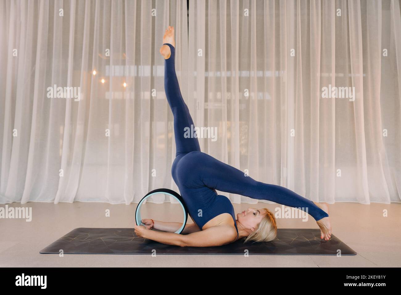 Una donna fa yoga con un anello Pilates, stretching il corpo, meditando la morbidezza di addestramento Foto Stock