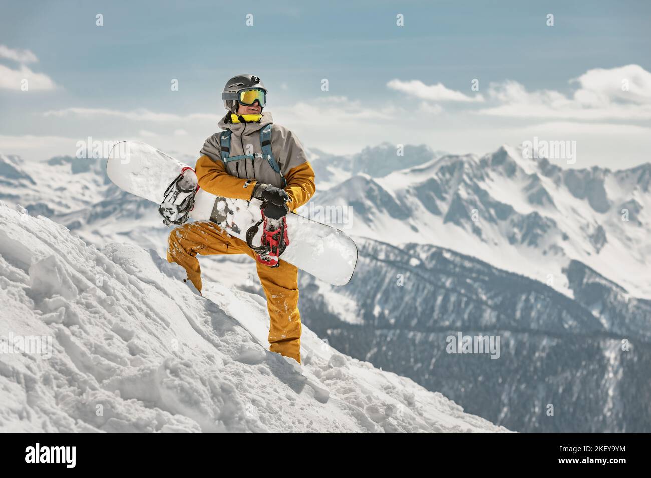 Bel snowboarder maschio si trova sulla pista da sci con lo snowboard in mano. Concetto di stazione sciistica Foto Stock