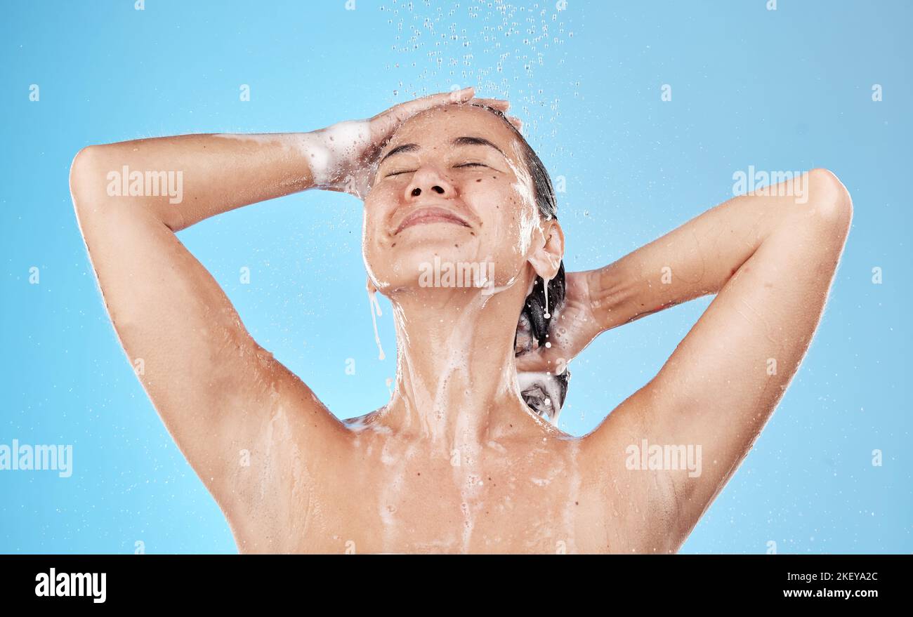 Bellezza, capelli e donna in doccia felice su sfondo blu, cura dei capelli e routine di igiene al mattino. Modello in acqua con schiuma di shampoo, pulizia Foto Stock