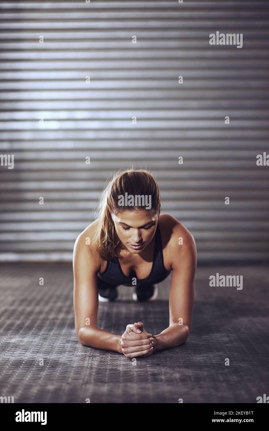 Le cose buone vengono a coloro che si sono arranati. Una giovane donna che fa un'esercitazione della tavola alla palestra. Foto Stock