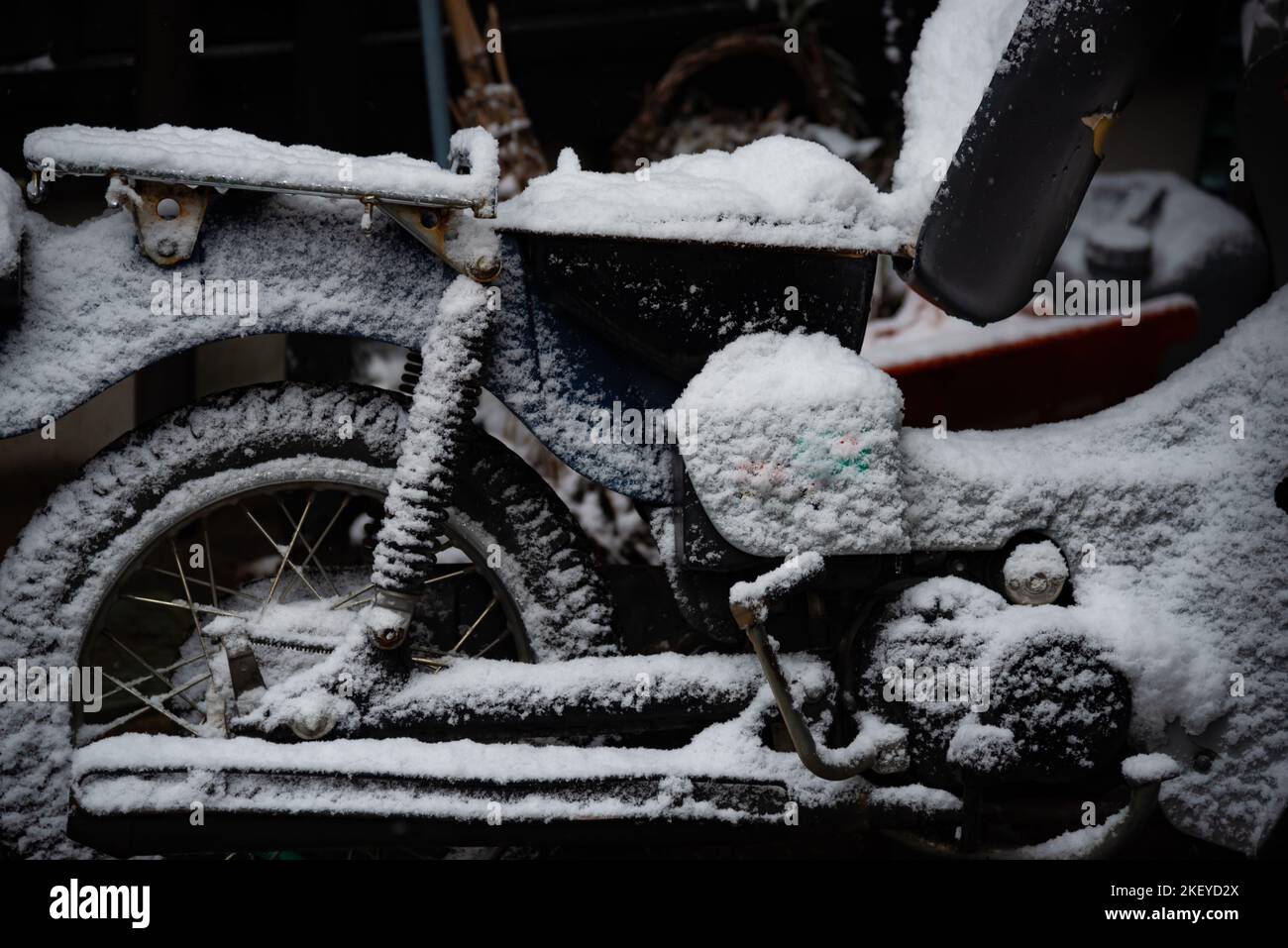 Abbattere la copertura del motociclo con la neve in inverno. Foto Stock