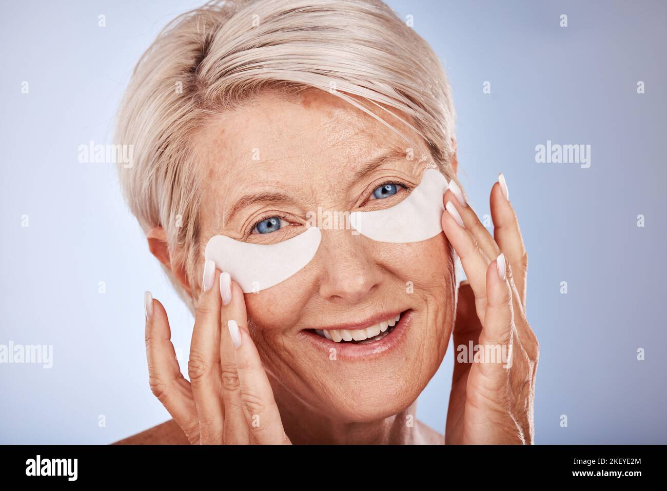 Donna anziana con collagene maschera occhi per la cura della pelle, dermatologia e il benessere del viso in studio mockup marketing o spazio pubblicitario. Modello anziano Foto Stock