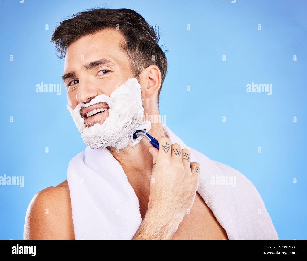 Viso, rasatura e epilazione con un modello uomo che rasa la pelle in studio  su sfondo blu per il benessere o l'igiene. Ritratto, barba e rasoio con  Foto stock - Alamy