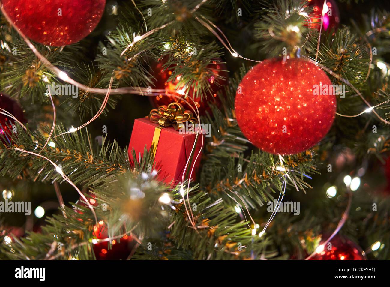 Foto ravvicinata delle palle rosse di natale e della confezione regalo sull'abete rosso decorato di Capodanno. Concetto di Natale Foto Stock