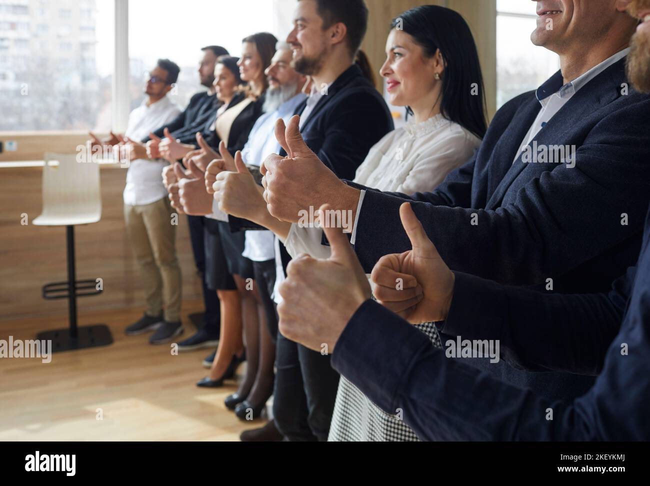 Le persone di affari positive danno i pollici fino a mostrare le loro azioni di approvazione gestione dell'azienda Foto Stock