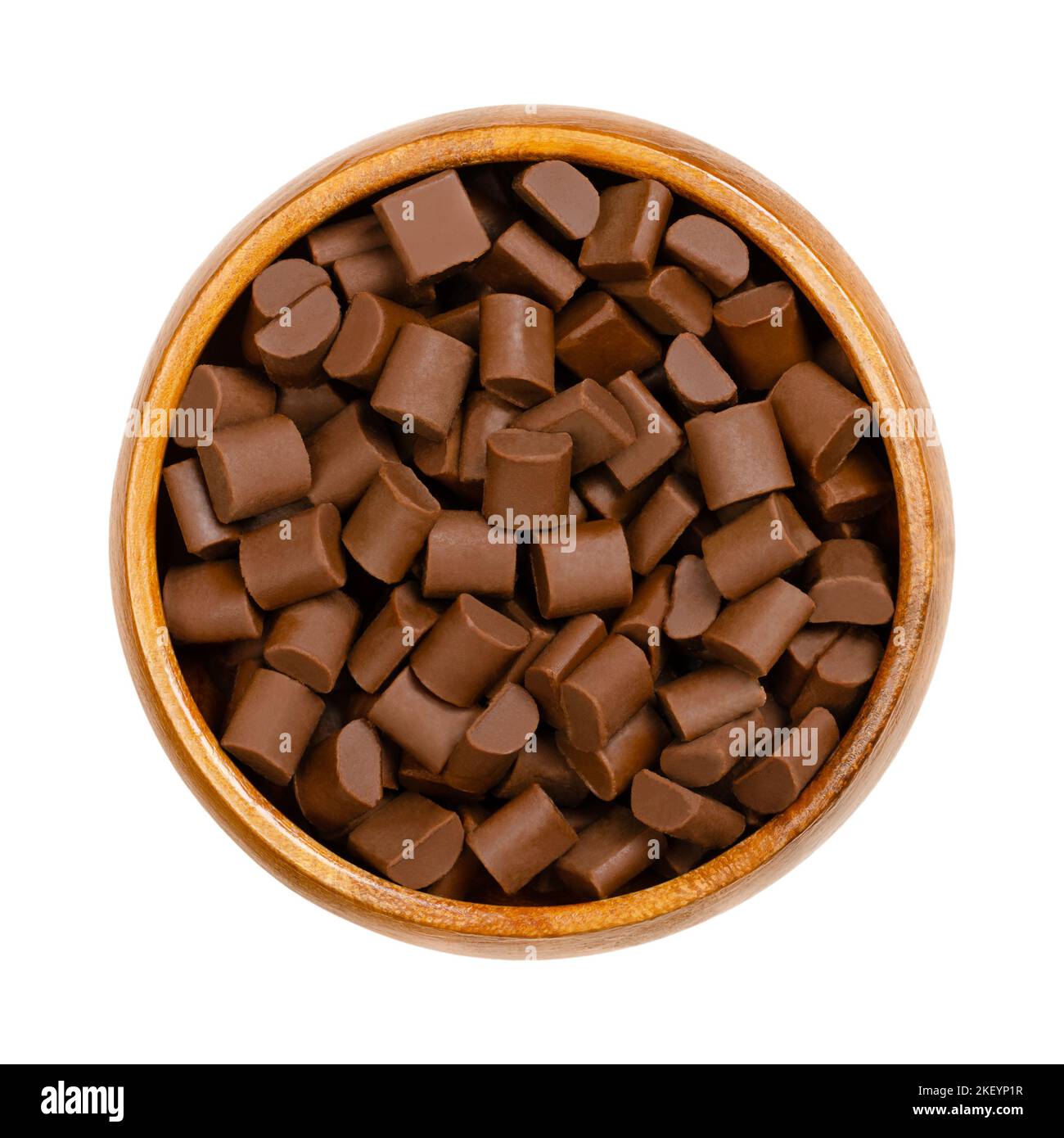 Pezzi di cioccolato, in una ciotola di legno. Patatine e piccoli bocconcini di cioccolato al latte, utilizzati come ingrediente in un certo numero di dolci. Foto Stock