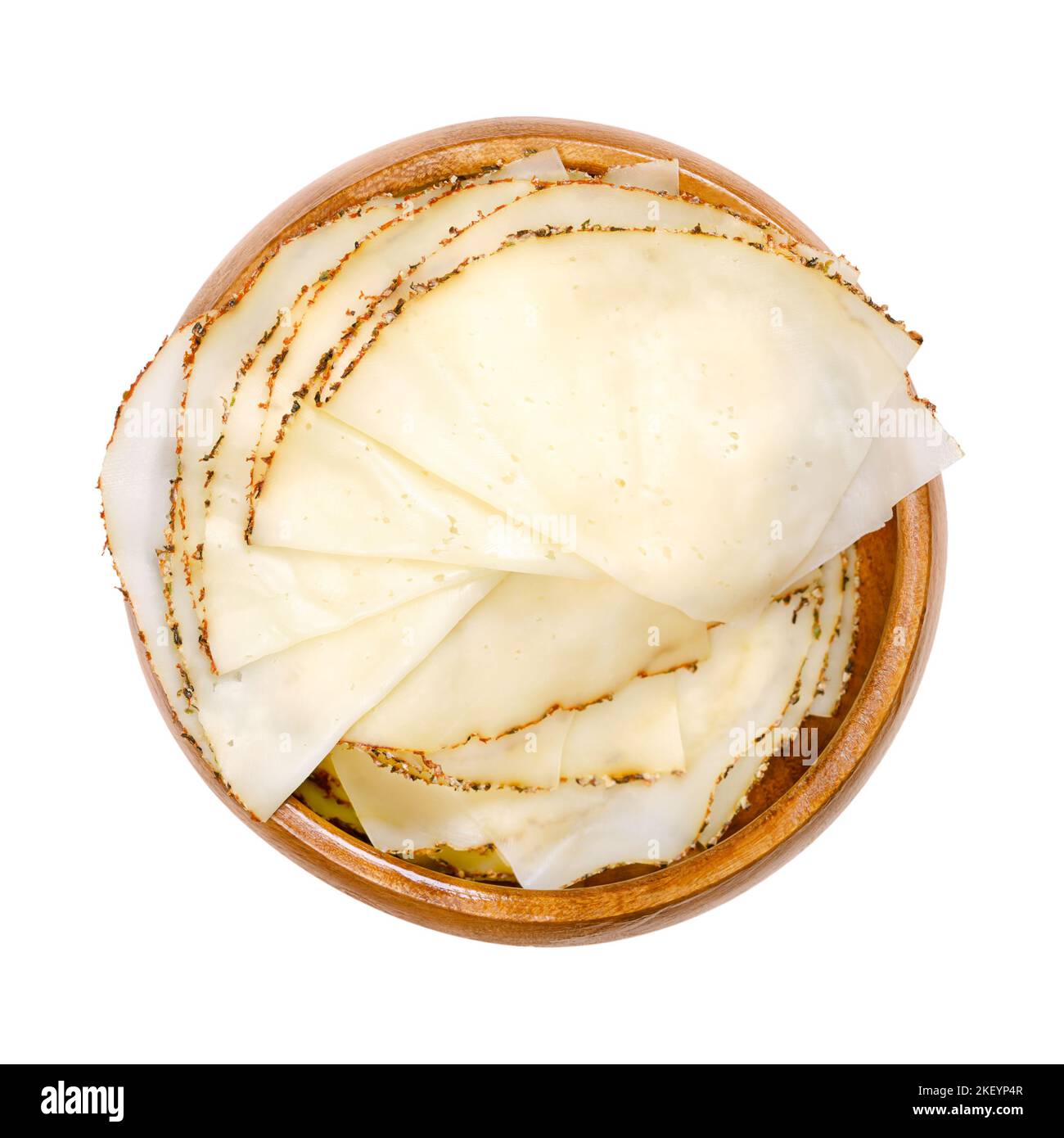 Formaggio al pepe a fette, trincee in una ciotola di legno. Formaggio morbido a fette extra fine, con un rivestimento di tre diversi grani di pepe. Foto Stock