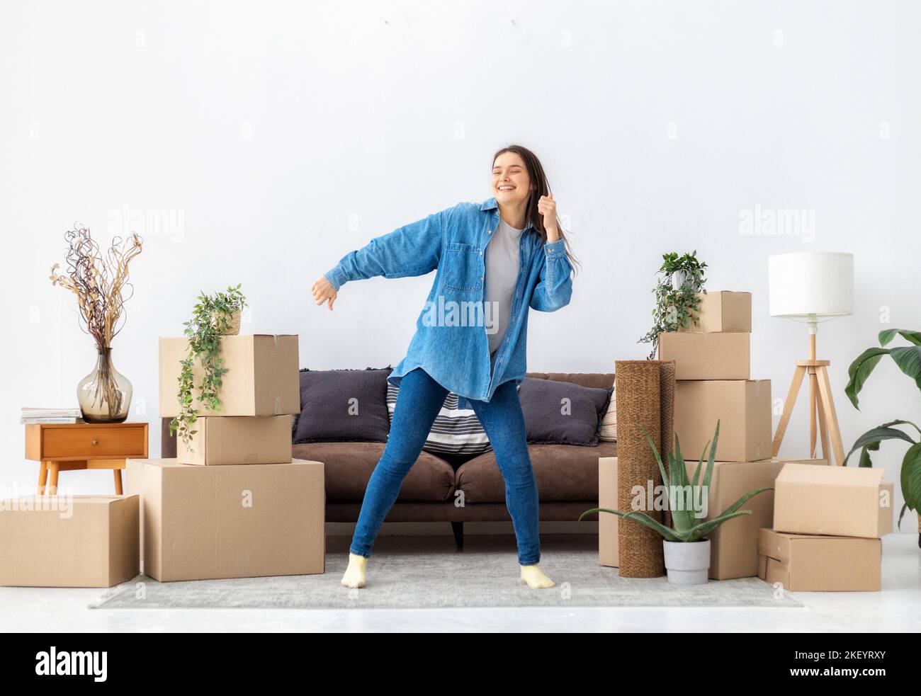 Giovane donna felice danza con felicità dopo essersi spostata nella sua nuova casa o appartamento Foto Stock
