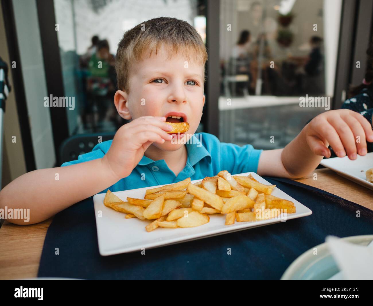 Piccolo bambino che mangia patatine fritte Foto Stock