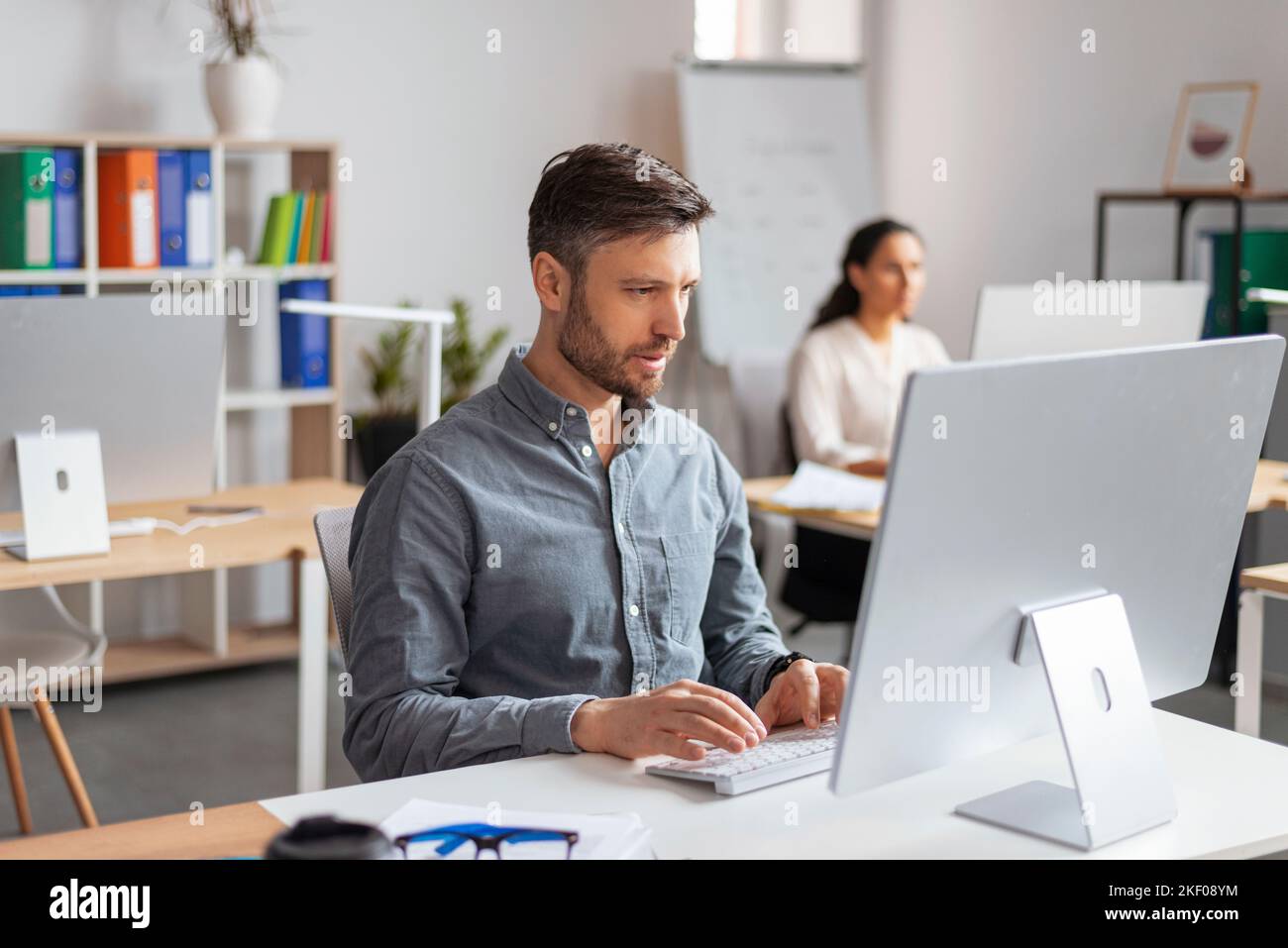 Uomo manager europeo millenario impegnato a digitare al computer sul posto di lavoro in un moderno ufficio interno Foto Stock