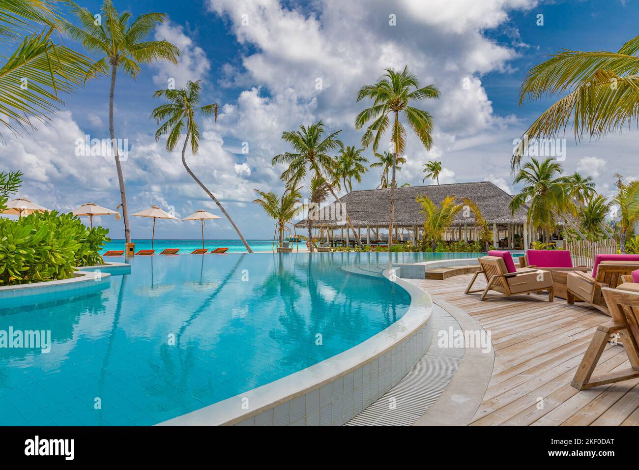 Incredibile turismo all'aperto paesaggio. Resort balneare di lusso con piscina mare sedie a sdraio lettini ombrelloni con palme Reflection Spa benessere Foto Stock