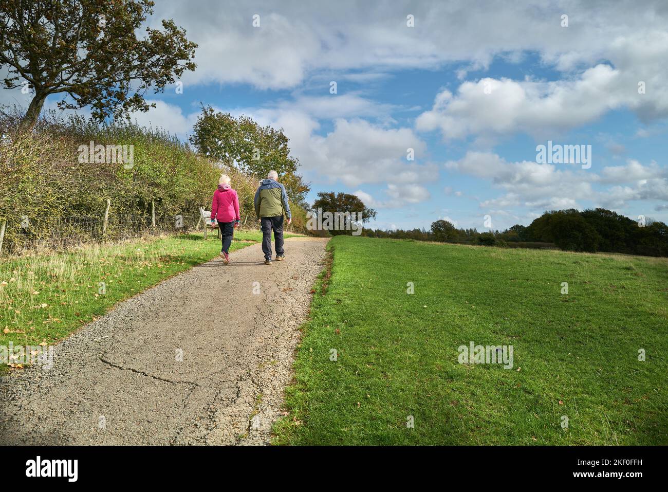 Una coppia anziana cammina lungo un sentiero in un parco contatiale inglese in un giorno d'autunno. Foto Stock