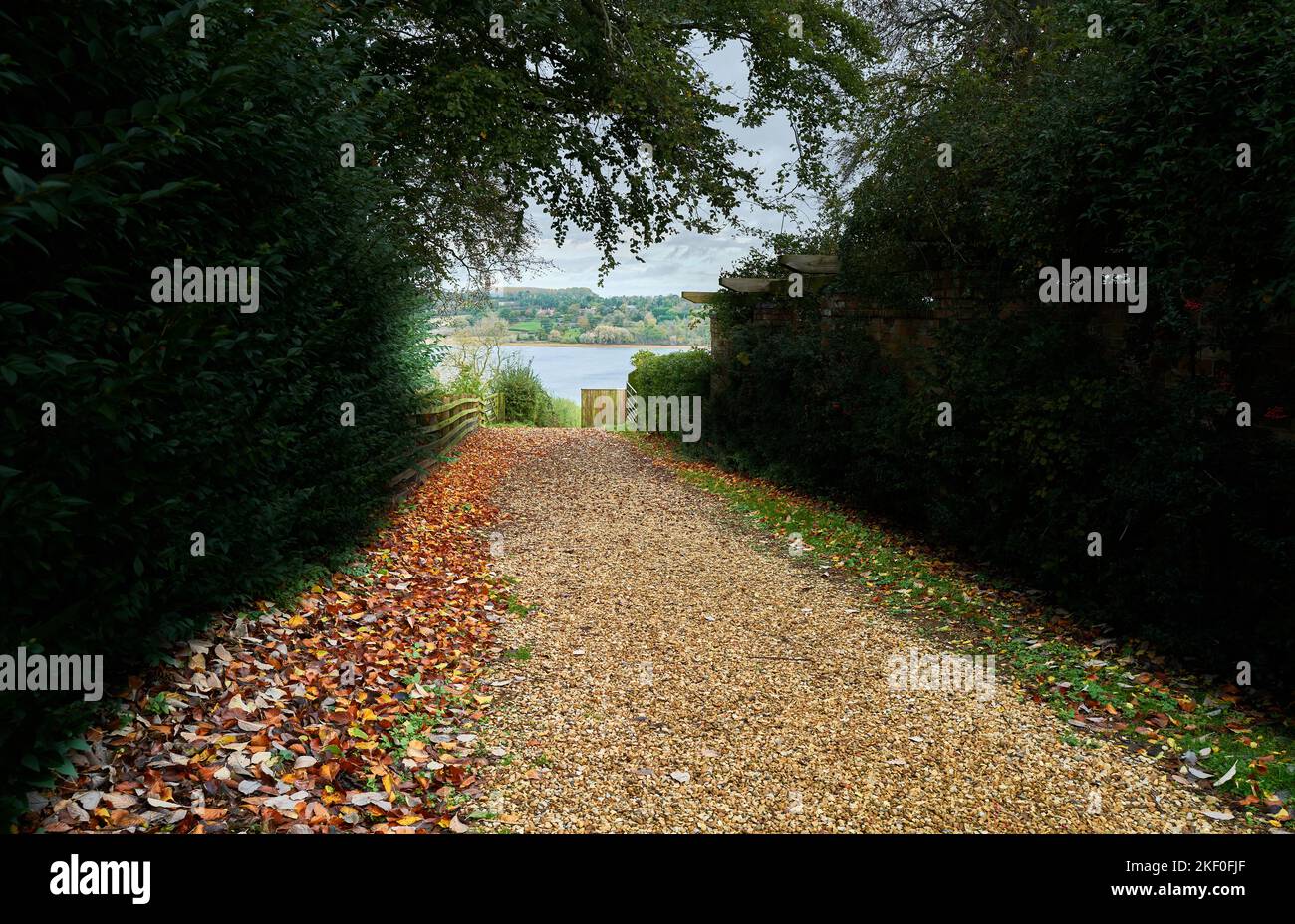 Sentiero costeggiato di foglie che conduce ad un lago in un parco contuale inglese in una giornata autunnale. Foto Stock