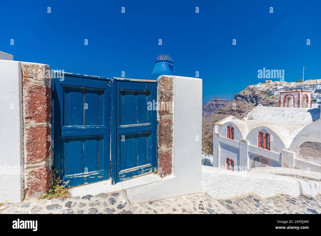 Fantastico sfondo di viaggio, il paesaggio urbano di Santorini. Porta o cancello blu con scale e architettura bianca sotto il cielo blu. Idilliaca vacanza estiva Foto Stock