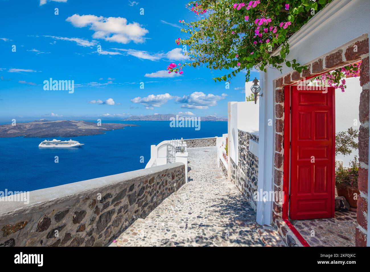 Un fantastico sfondo di viaggio, il paesaggio urbano di Santorini. Porta o cancello rosso con scale e architettura bianca sotto il cielo blu. Idilliaca vacanza estiva Foto Stock