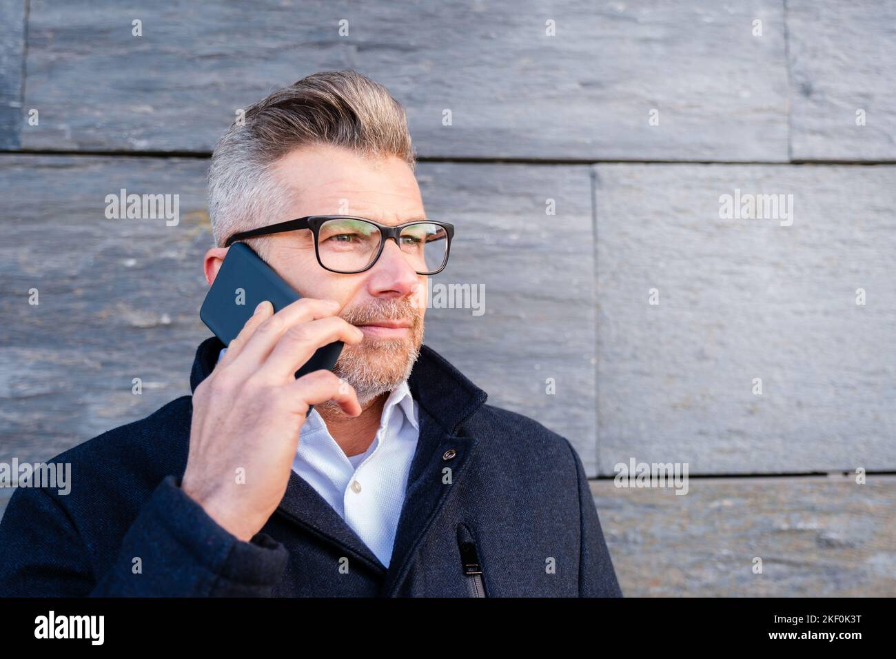 Ritratto di uomo d'affari in occhiali che parlano su smartphone Foto Stock