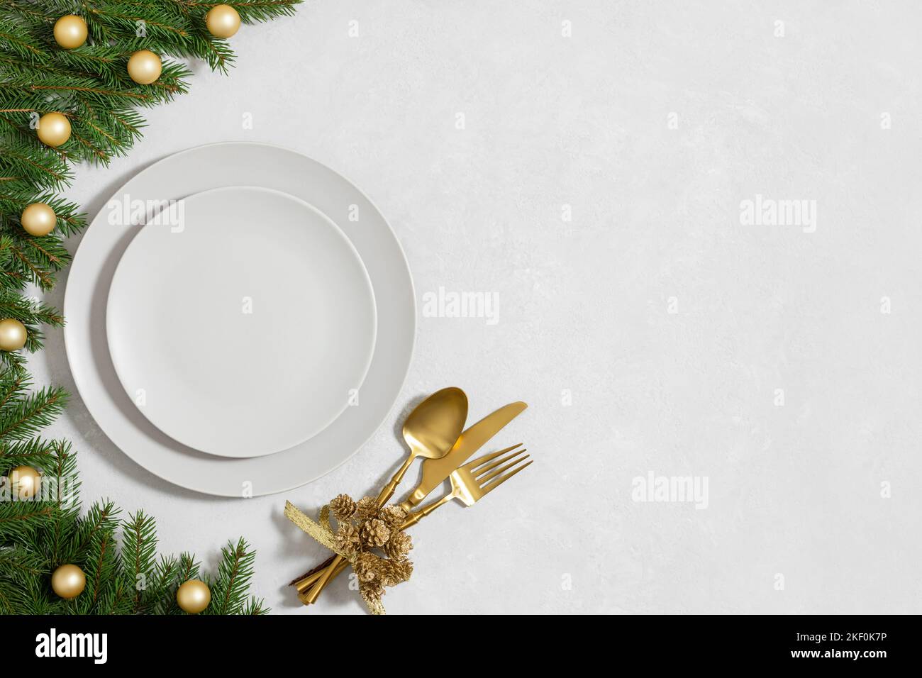 Tavolo d'oro di Natale e su sfondo grigio. Piastra vuota per la progettazione. Festa di Capodanno. Spazio di copia, vista dall'alto, disposizione piatta. Foto Stock
