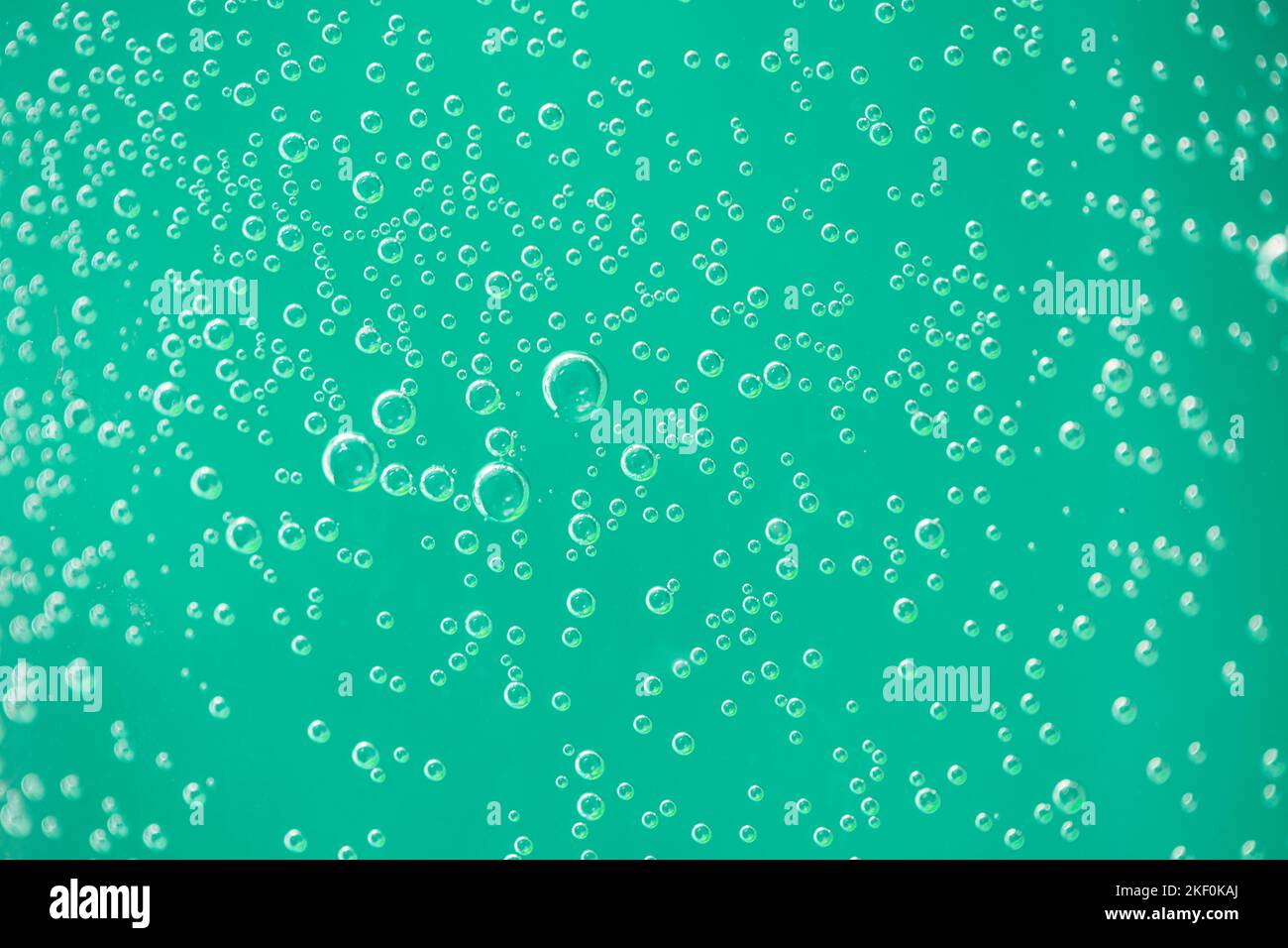Gocce d'acqua sul vetro su sfondo verde. Macro artistica sotto la luce naturale, gocce d'aria su sfondo di vetro Foto Stock