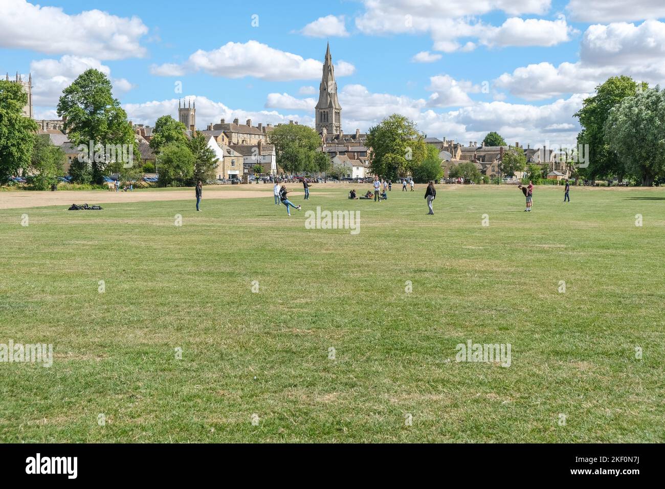 Estate 2022. I giovani giocano a calcio sui Meadows a Stamford, con tre delle chiese di Stamford sullo sfondo. Lincolnshire, Inghilterra Foto Stock