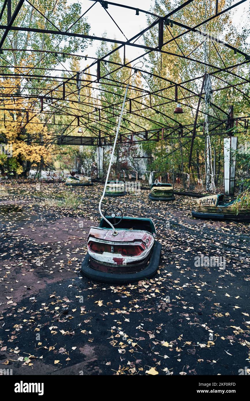 Abandoned Amusement Car Ride nella città fantasma di Pripyat nella zona di esclusione di Chernobyl, scooter nei colori autunnali Foto Stock
