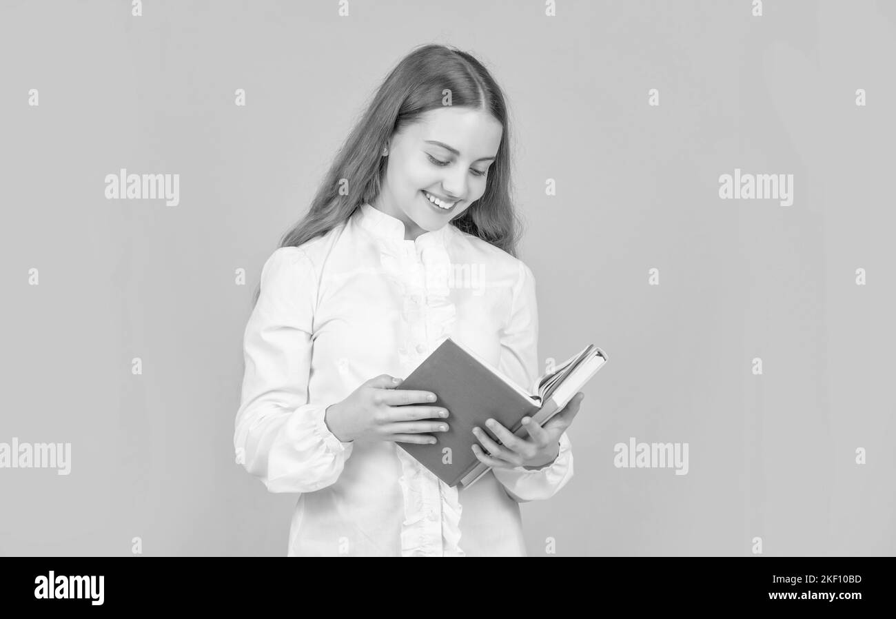 ragazza teen felice in camicia bianca pronta a studiare fare i compiti leggere libro su sfondo giallo, lettore Foto Stock