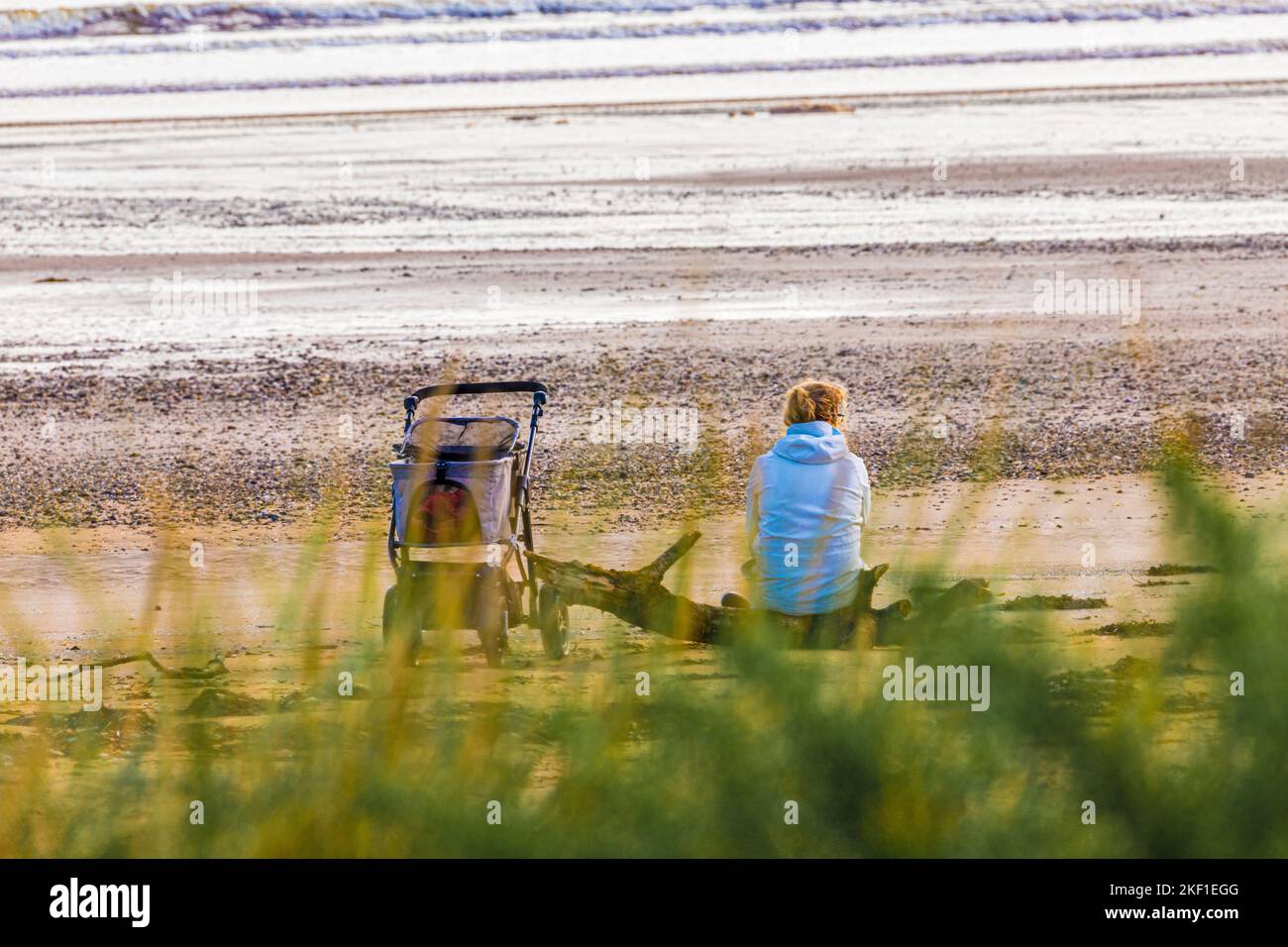 Una donna solitaria con un passeggino sulla spiaggia a Carradale Bay sulla penisola di Kintyre, Argyll & Bute, Scozia UK Foto Stock