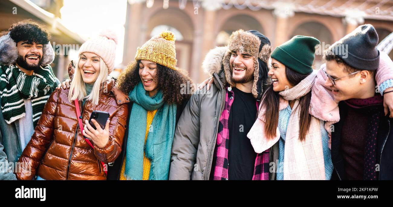 Felice gruppo di studenti a piedi nella città europea il giorno di sole - Next gen z concetto di stile di vita con i giovani multirazziali indossare abiti invernali Foto Stock