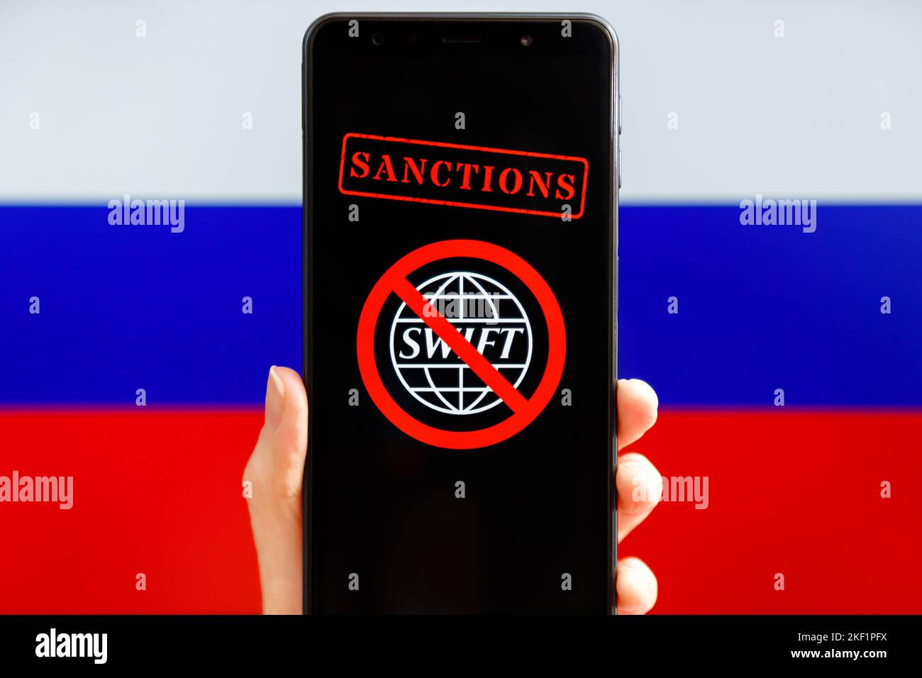 Ucraina, Kiev - Febbraio 23 2022: Mobile con logo SWIFT barrato e bandiera russa sullo sfondo. Sanzioni contro la Russia, disconnessione Foto Stock