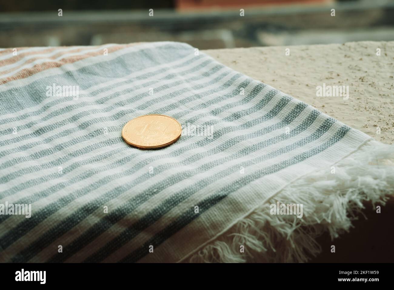 Bitcoin Coin si trova sulla spiaggia Towel sullo sfondo della piscina Hotel a Moraitika, Corfù, Grecia. Il concetto di pagamento per relax e senza limiti Foto Stock