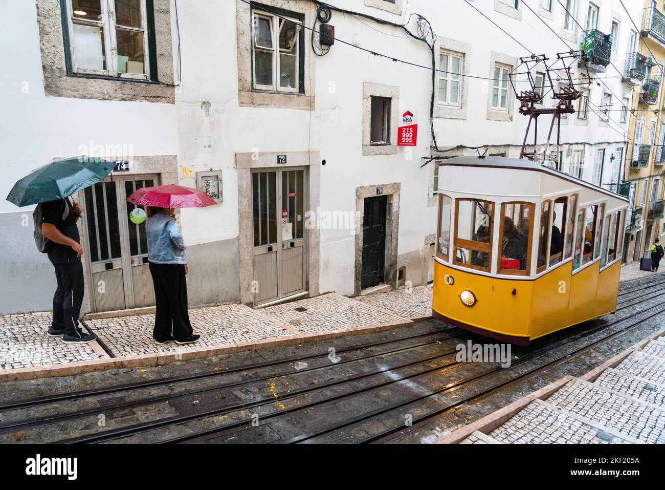 OMBRELLONI: Durante una pioggia torrenziale i turisti riempiono la famosa Bica - LG. Tram collinare Calhariz a Lisbona, Portogallo. Foto Stock