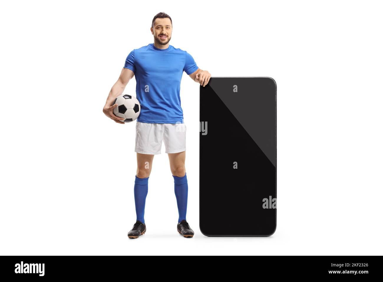 Ritratto completo di un giocatore di calcio in piedi accanto a un grande smartphone isolato su sfondo bianco Foto Stock Ritratto completo di un giocatore di calcio in piedi accanto a un grande smartphone isolato su sfondo bianco Foto Stock