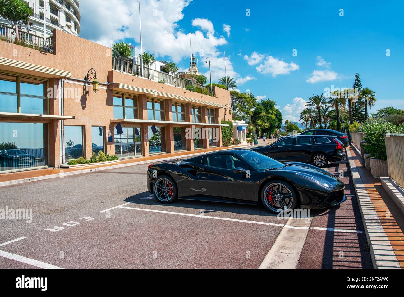 Auto di lusso vicino ai casinò nel quartiere di Monte Carlo di Monaco in splendida estate soleggiata. Dietro lo splendido parco sono presenti palme e aiuole fiorite Foto Stock