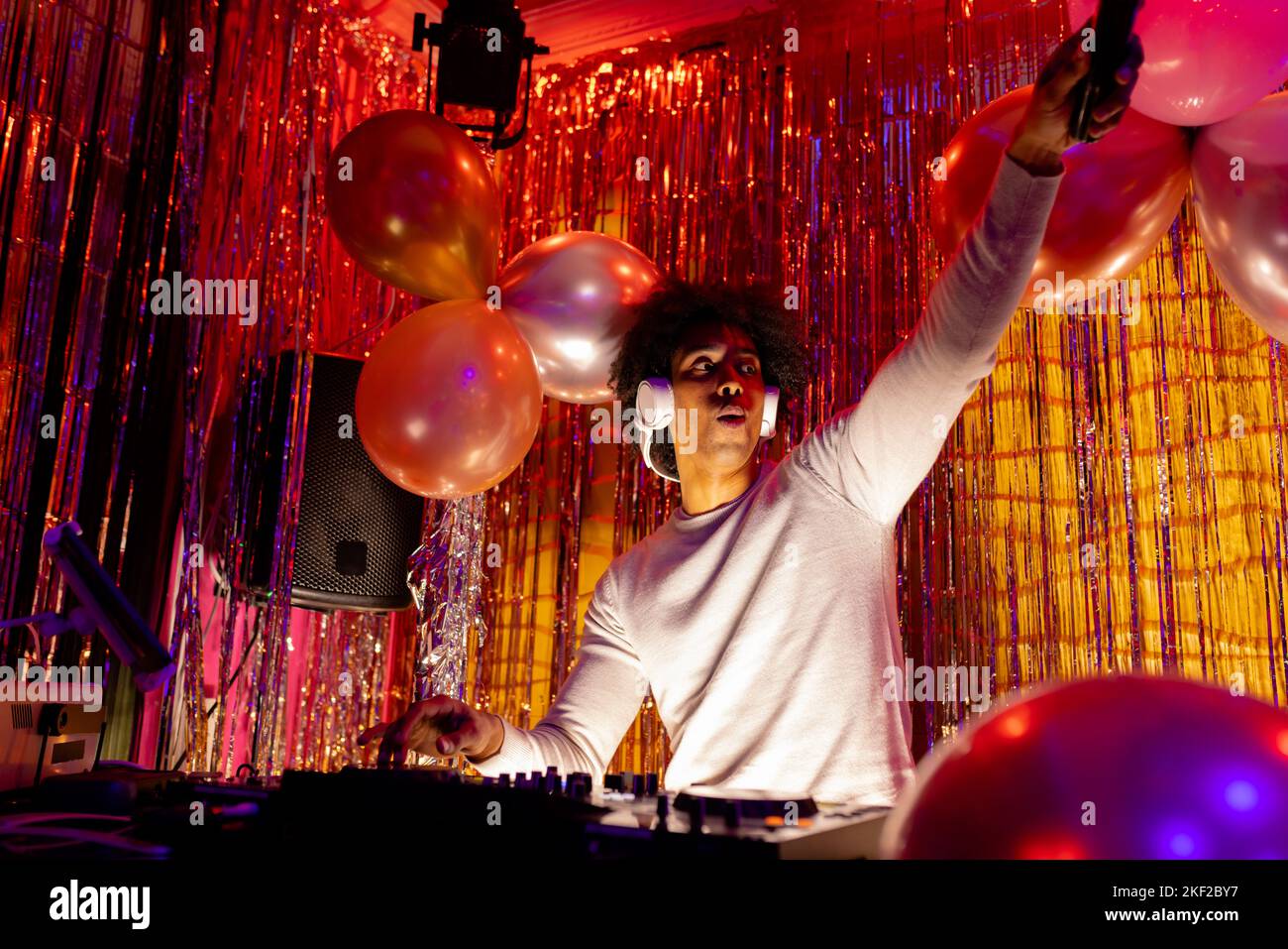 Dj afro-americano in cuffie che suonano musica in un nightclub e tenendo il microfono Foto Stock